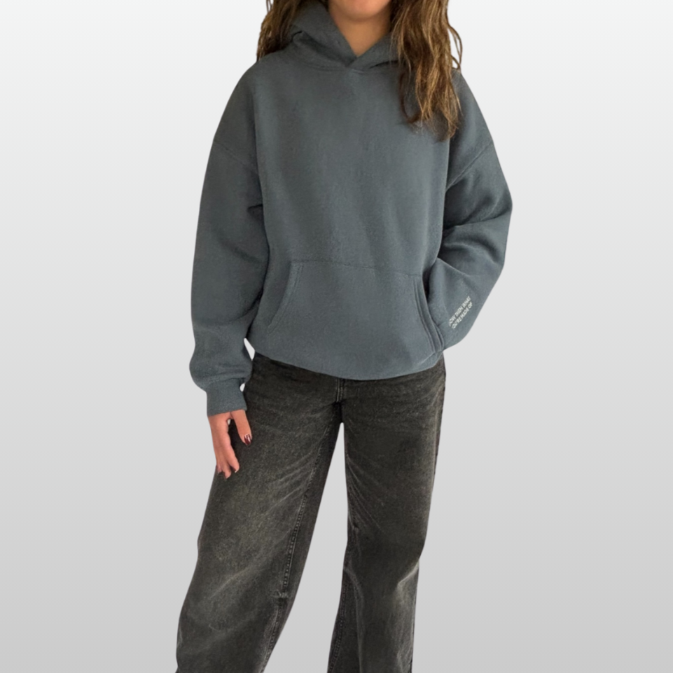Person wearing a gray hoodie and dark pants on a white background