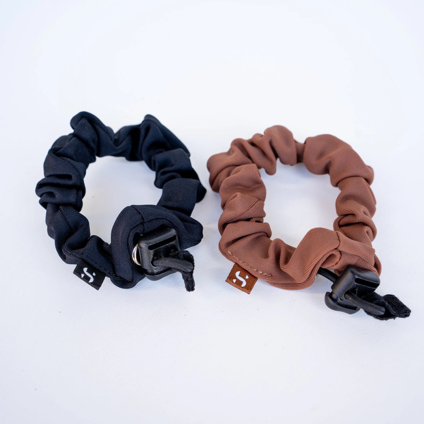 Two scrunchies, one black and one brown, on a white background