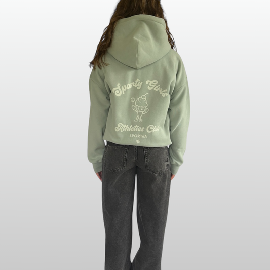 Person wearing a green hoodie with text and graphics on the back, standing against a white background