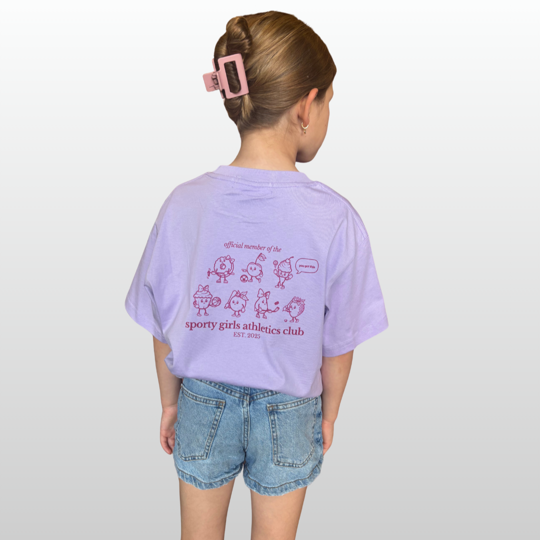 Child wearing a light purple t-shirt with graphics and text, standing against a plain background