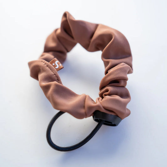 Brown scrunchie with a black elastic band on a light gray background
